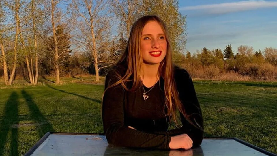 Sarah Strate souriante assise dans un parc.