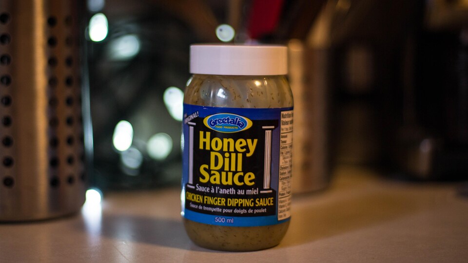 Un pot de sauce avec une étiquette bleue sur un comptoir.