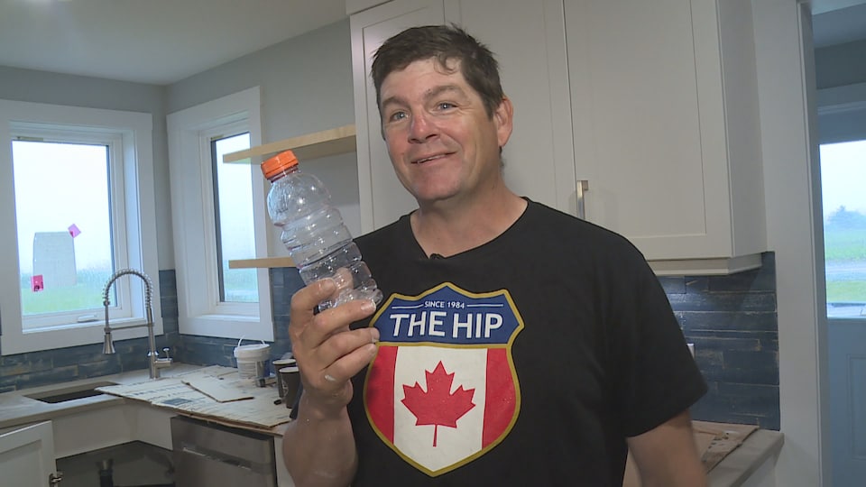 David Saulnier dans la cuisine de la nouvelle maison tient une bouteille de plastique en main