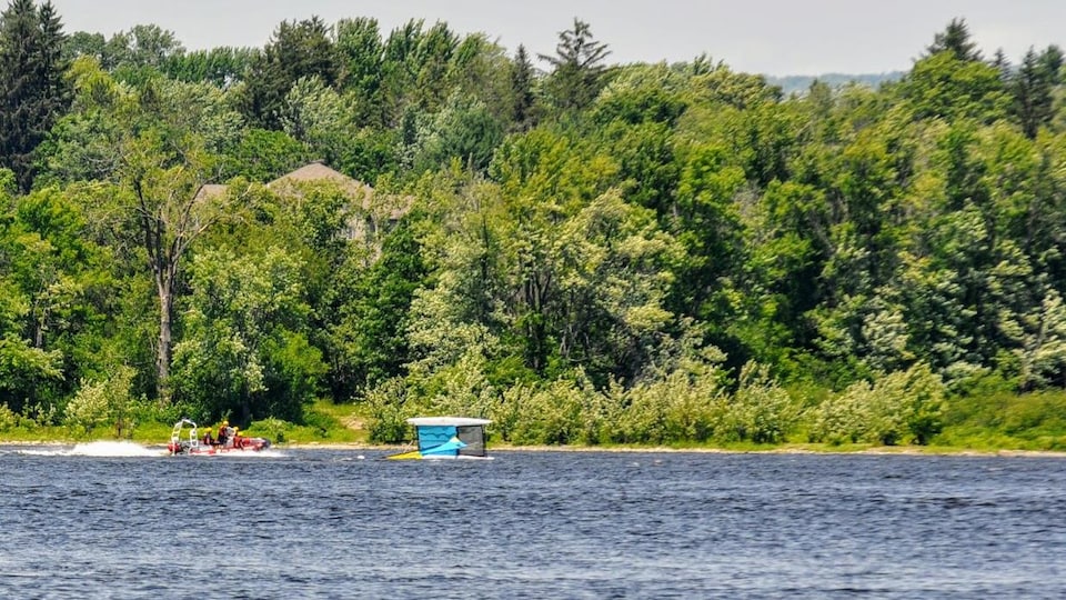 Un bateau de secours s'approche d'une embarcation renversée.