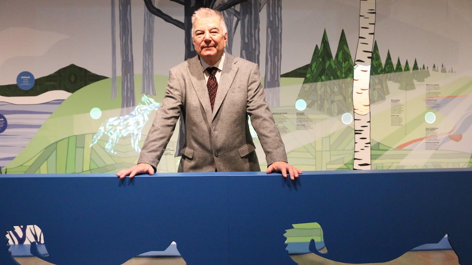 Un homme se tient debout en costume avec en fond des dessins de paysages nordiques