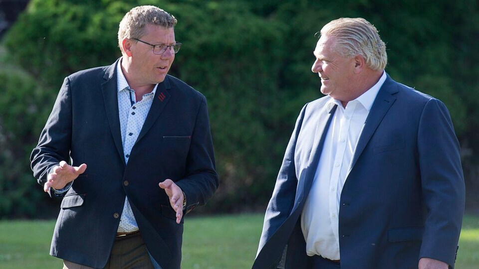 Scott Moe parle à Doug Ford dans un parc.