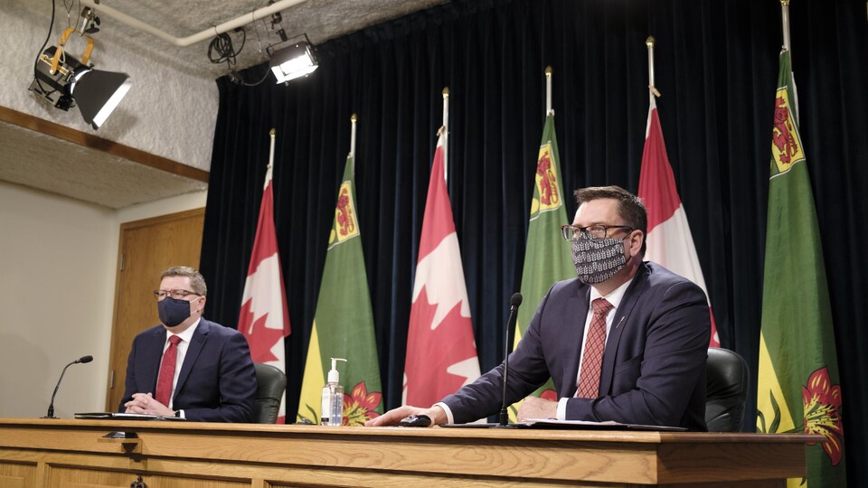 Scott Moe et Paul Merriman portent le masque lors d'une conférence à l'Assemblée législative de la Saskatchewan.
