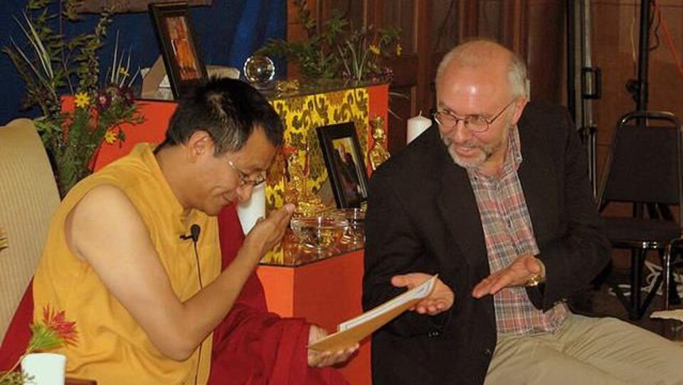 Scott Wellenbach devant un moine bouddhiste qui consulte un texte.