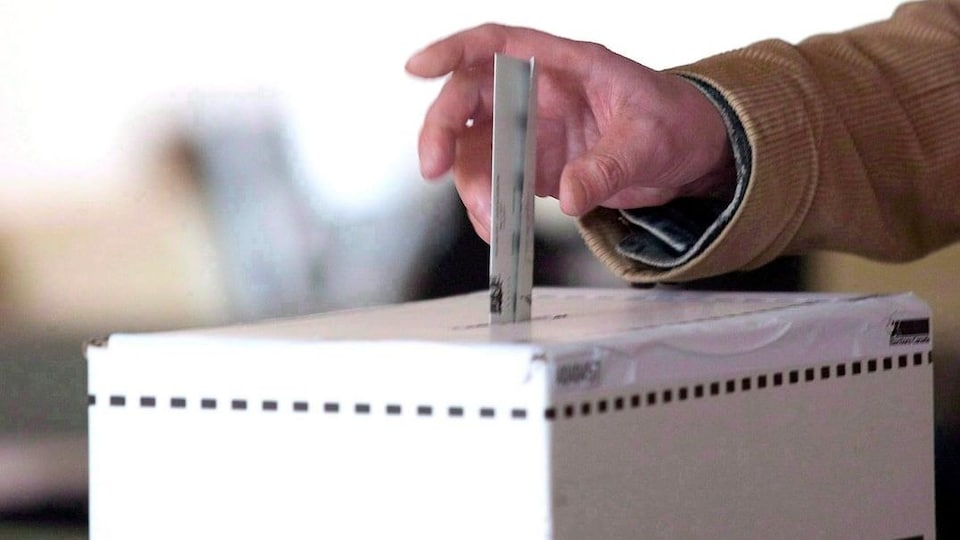 Un électeur dépose son bulletin de vote dans une boîte de scrutin. 