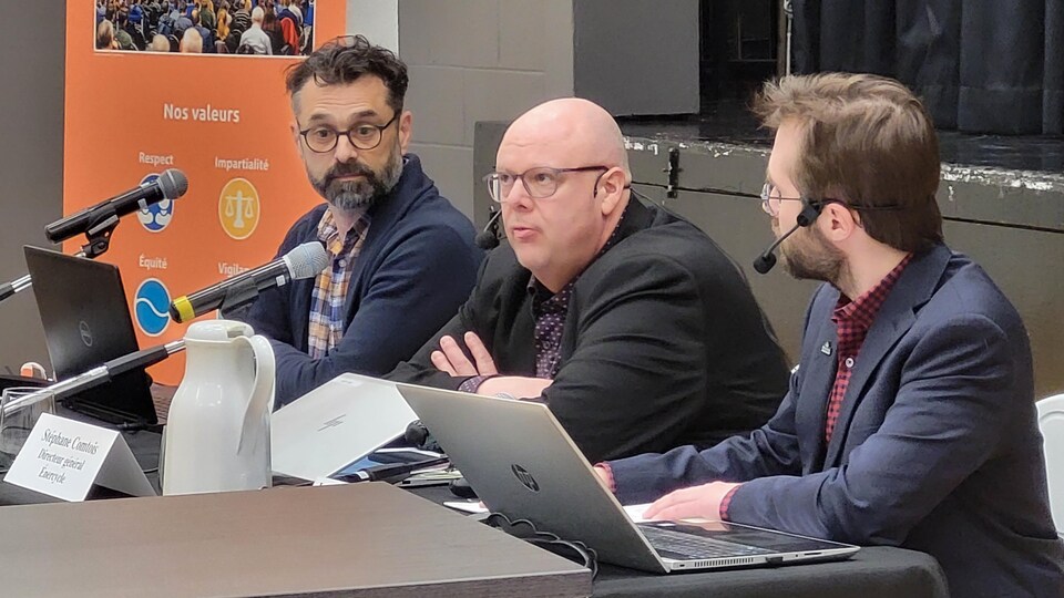 Trois hommes assis à une table.