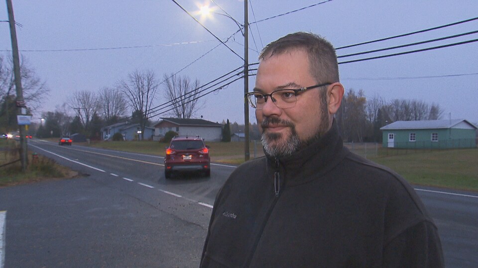 Un homme répond aux questions des journaliste près d'une rue passante