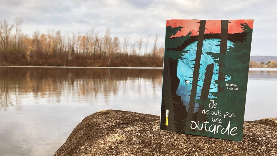 Un livre de Sébastien Gagnon repose sur un rocher se trouvant à proximité d'un cours d'eau. 
