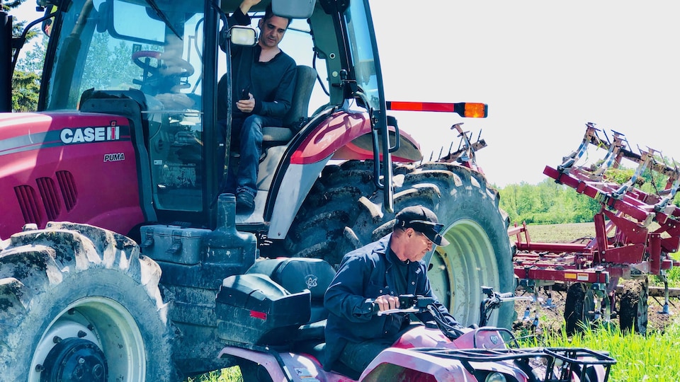 Sébastien Gaudreault est dans son tracteur alors que son ami s'approche pour l'aider à descendre.
