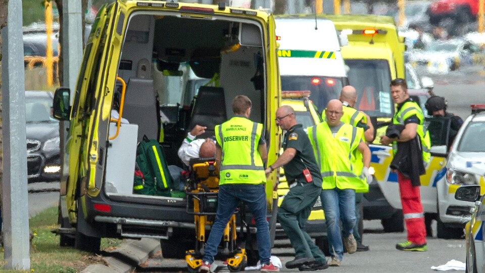 Des ambulanciers montent une civière dans une ambulance.