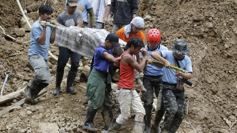 Des secouristes transportent le corps d'une victime qui s'est retrouvée ensevelie lors d'un glissement de terrain à Itogon, dans le nord des Philippines.