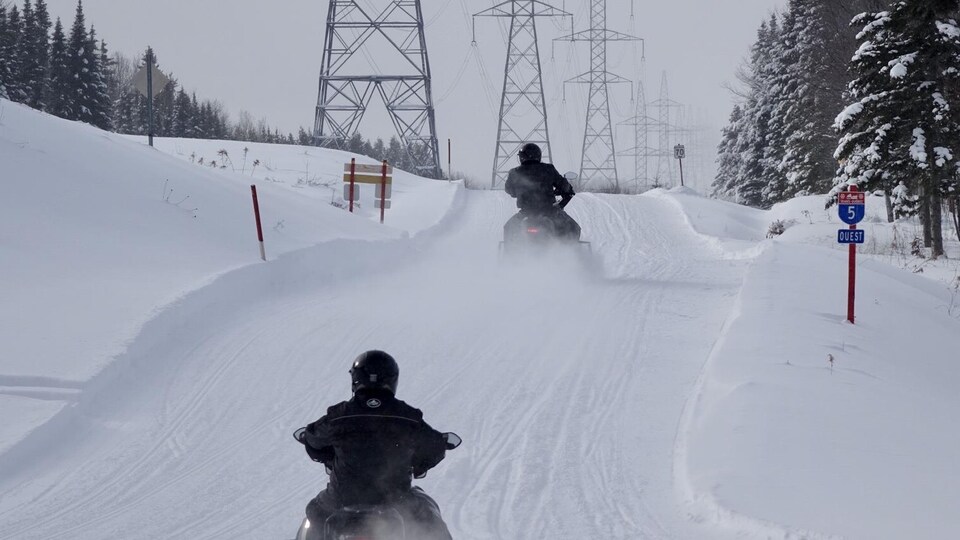 Deux motoneigistes sur la route blanche