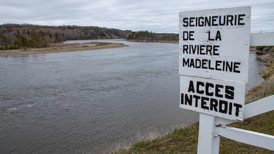 Un panneau inscrit accès interdit sur le bord d'une rivière.