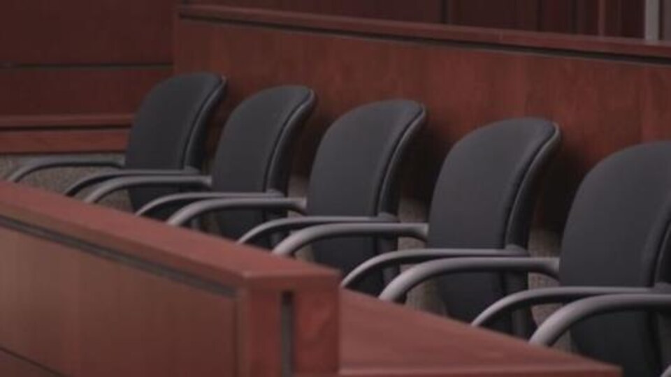 On aperçoit un box de jurés vide dans un tribunal.