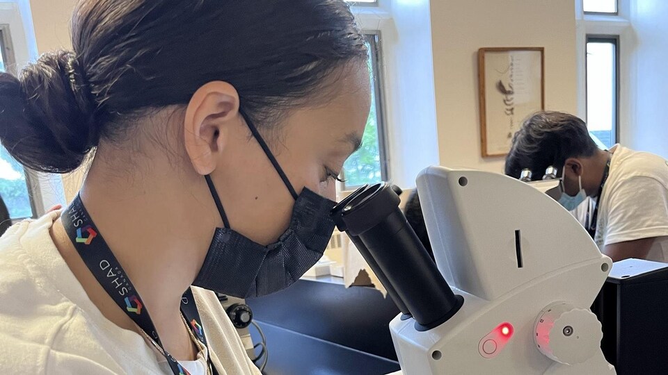 Neila Selouani utilise un microscope dans un laboratoire.