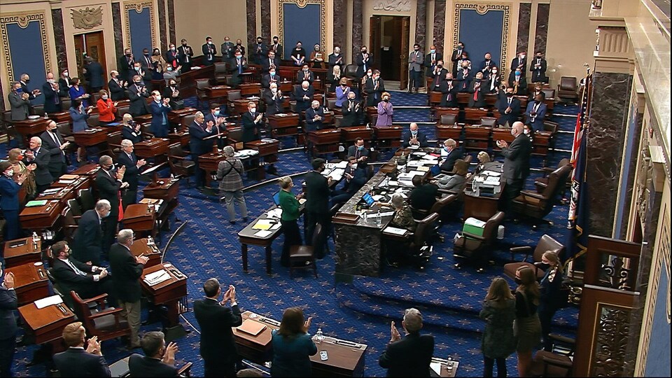 Au sein de la Chambre haute, des sénateurs se tiennent debout et applaudissent.