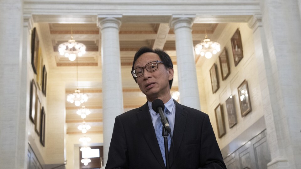 Yuen Pau Woo debout devant des colonnes blanches. 