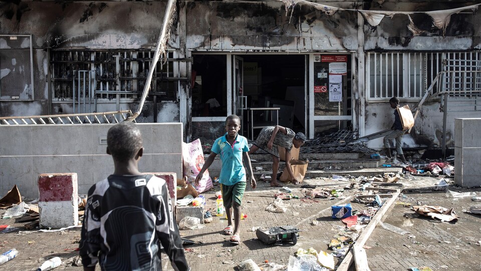 Des enfants devant un supermarché incendié et pillé