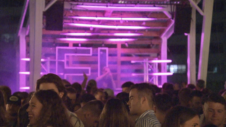 Scène avec une DJ devant une foule d'étudiants dans la vingtaine.