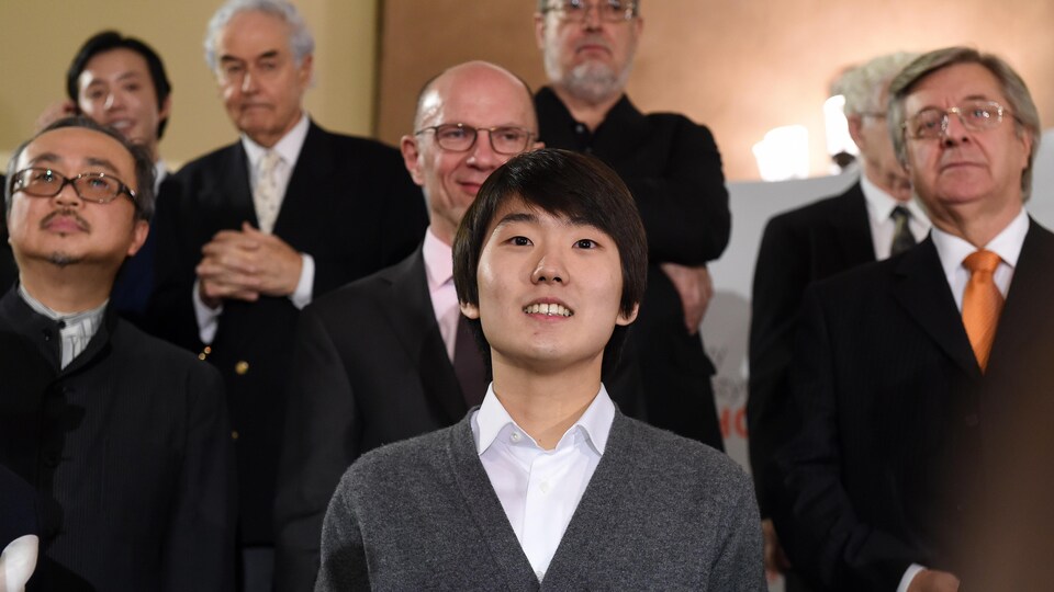 Un homme pose devant une foule d'hommes après avoir remporté le prix Chopin.