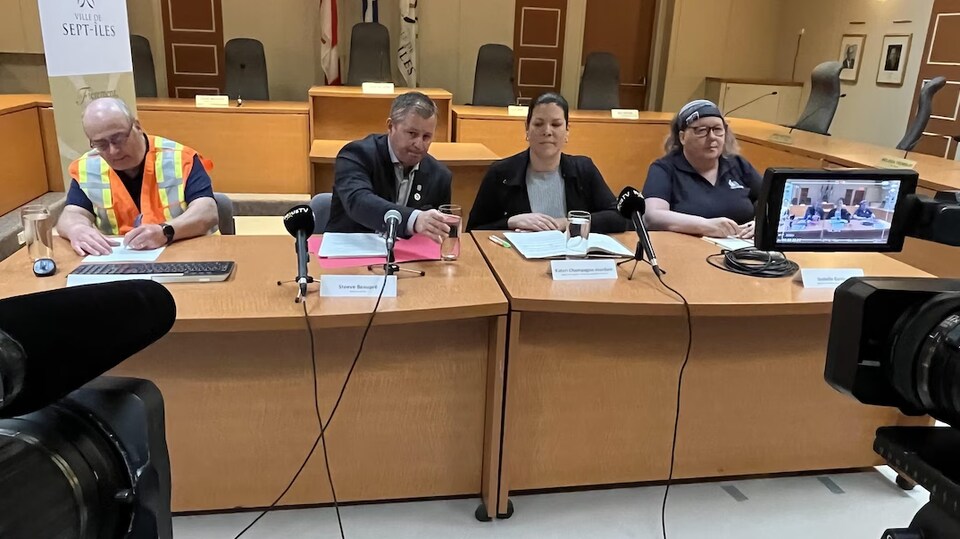 Des gens siègent à une table en conférence de presse.