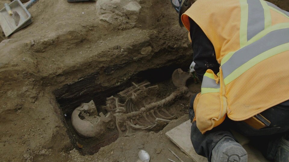 Un scientifique penché sur un squelette dans une sépulture.