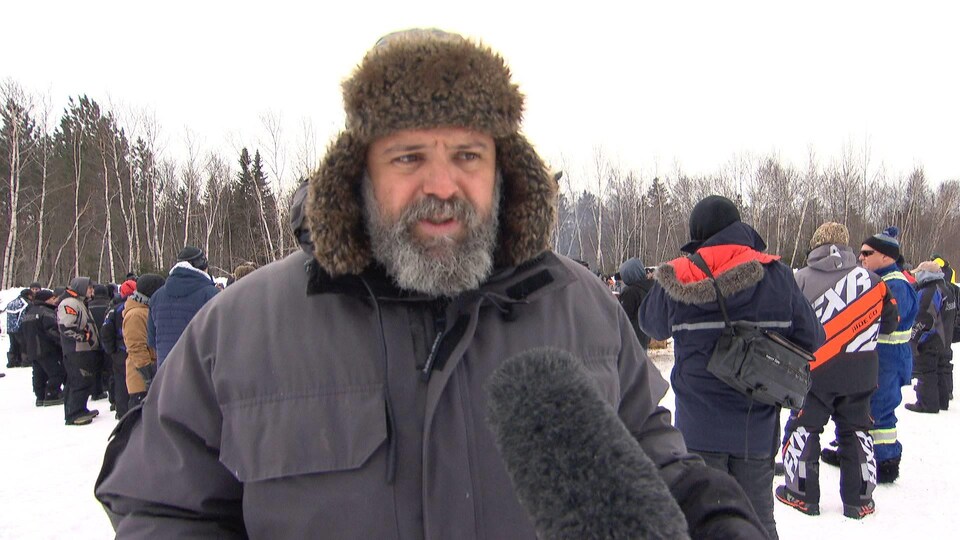 Serge Brideau accorde une entrevue à l'extérieur pendant une manifestation.