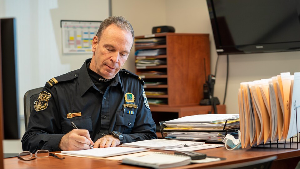 Luc Mongrain dans son bureau qui écrit.