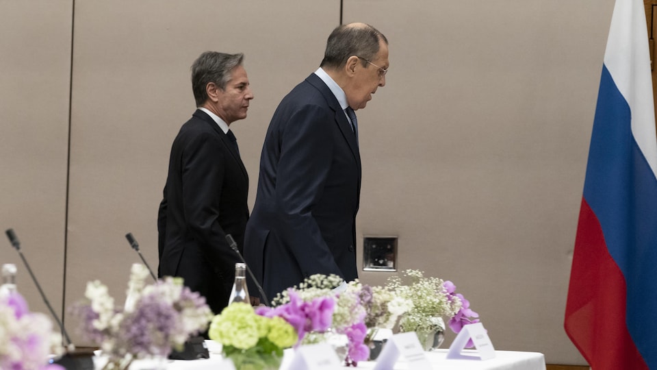 Antony Blinken marche derrière Sergueï Lavrov dans une salle.