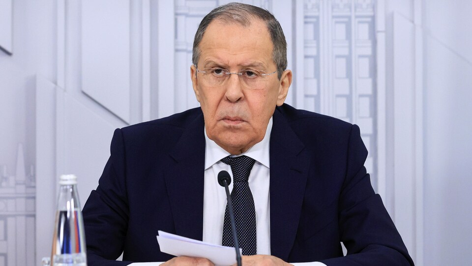 Sergueï Lavrov, assis devant un micro, avec une feuille entre ses mains. 