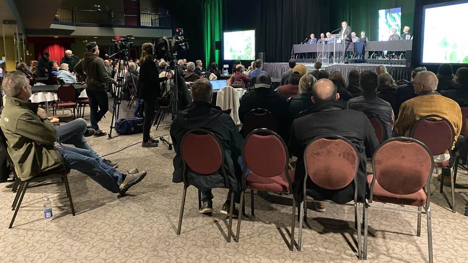 Des gens écoutent une présentation dans une salle.