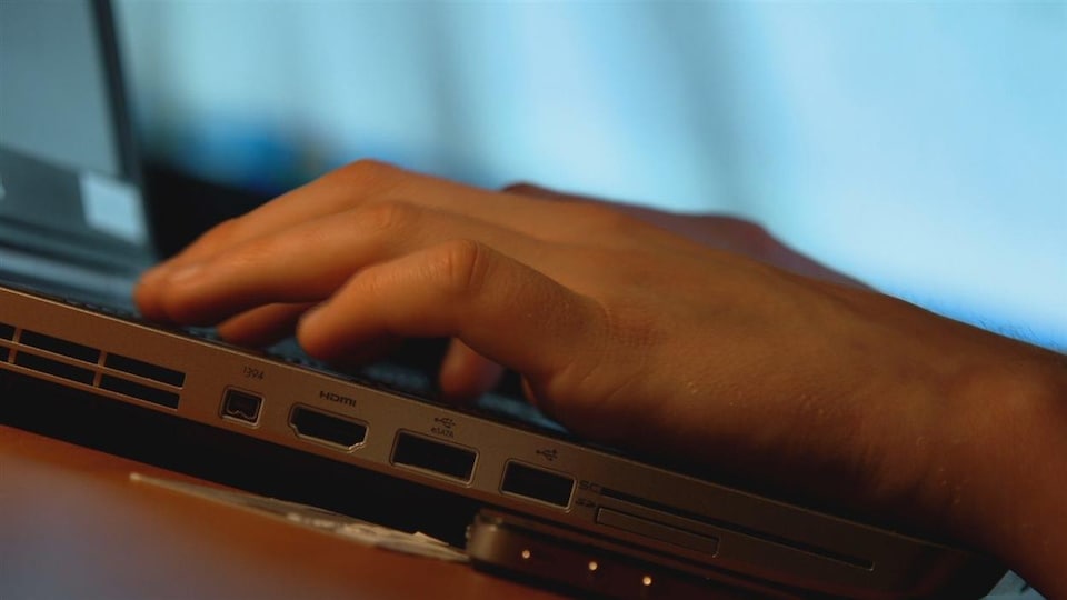 Des mains sur un clavier d'ordinateur.