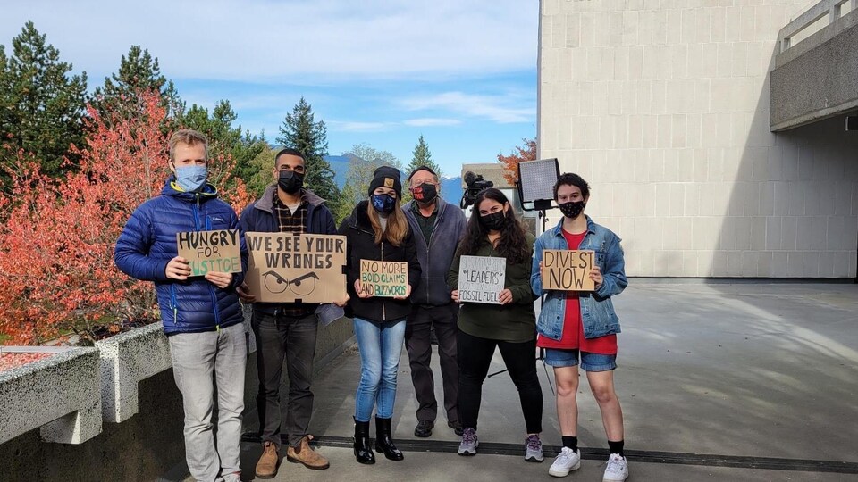 Des étudiants de l'Université Simon Fraser tiennent des pancartes sur lesquelles sont inscrits des slogans.