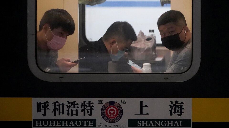 Des passagers dans un train portant un masque. 