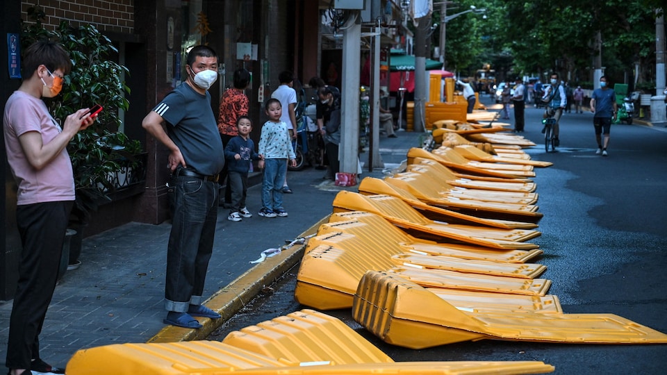 Residents, masked, watched as barriers fall to the ground.