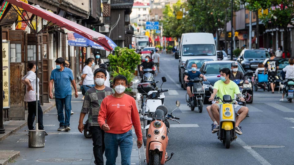 The men are walking down the street wearing masks.