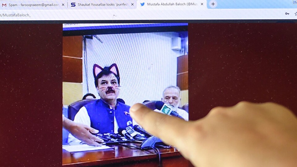 Un enfant pointe du doigt la capture d'écran d'un homme affublé d'oreilles de chat virtuelles.