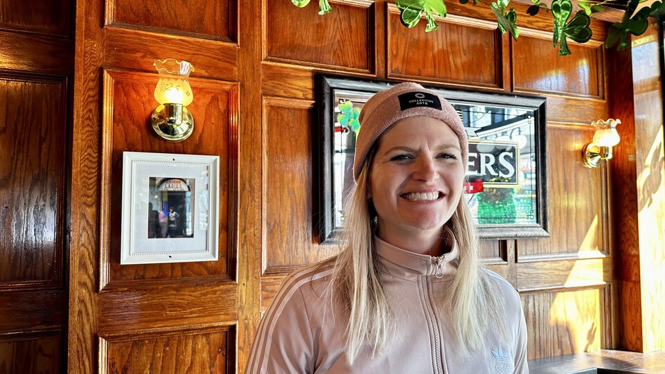 Une femme pose pour la photo à l'intérieur d'un bar. 