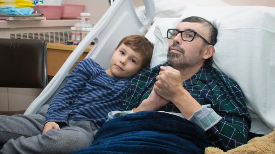 Un homme avec son fils sur un lit d'hôpital.