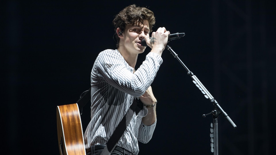 Shawn Mendes, on his show at the Festival d’été de Québec in 2018, sings into the microphone.