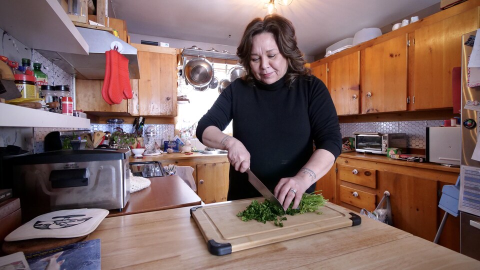Une femme coupe des herbes fraîches dans sa cuisine.