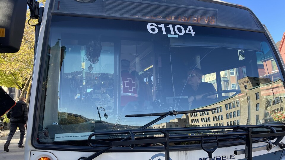 Gros plan d'un autobus de Sherbrooke. À l'intérieur, on peut voir un employé de la Croix-Rouge.