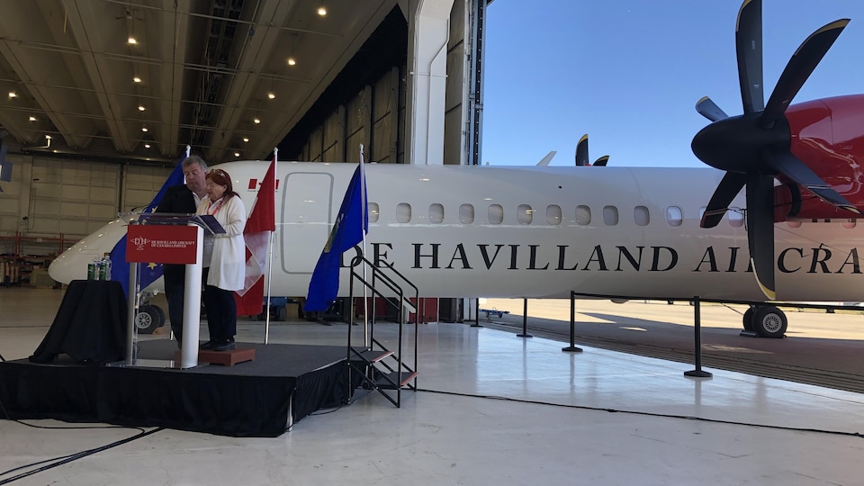 Sherry Brydson et son mari sur un podium devant un avion De Havilland.
