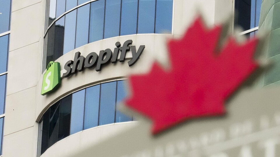 Le logo de Shopify se détache devant l'immeuble, derrière une feuille d'érable.