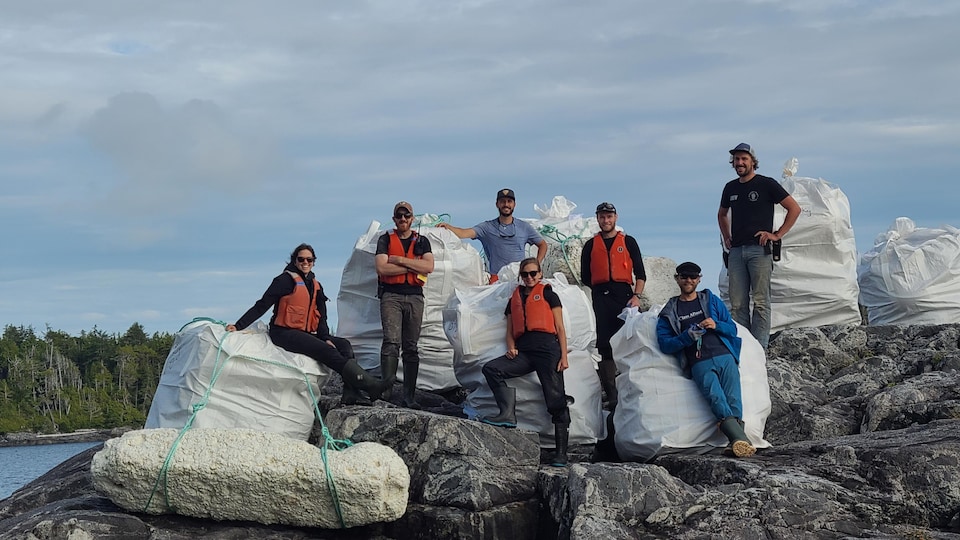 Des membres de l'équipage de Bluewater Adventures posent devant les sacs contenant les débris ramassés.