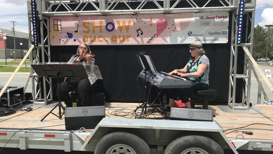 Une violoniste et une pianiste jouent de la musique sur une remorque.