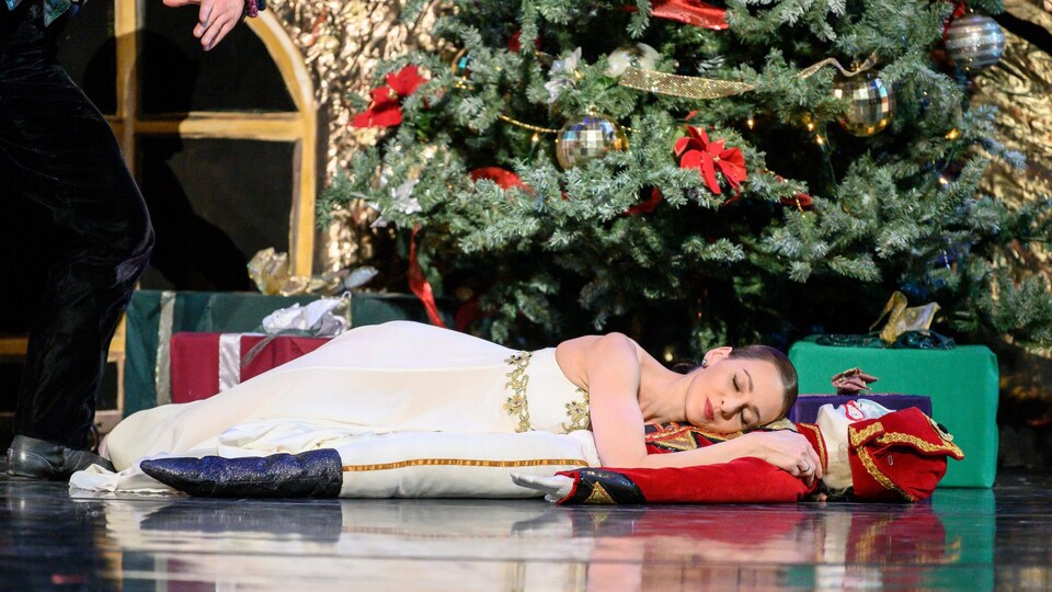 Une femme dort devant un sapin de Noël.