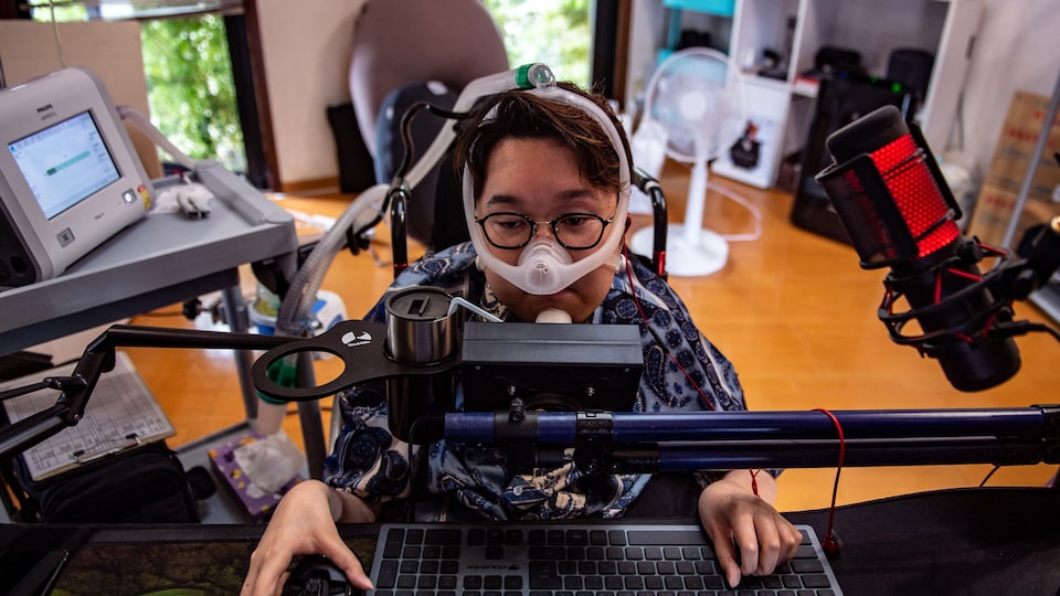 Une personne handicapée joue à des jeux vidéo dans son salon avec de l'équipement adapté. 
