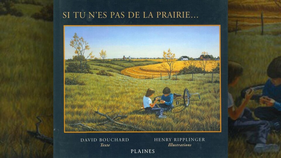 Deux enfants sont assis dans de l'herbe avec un vélo couché par terre.