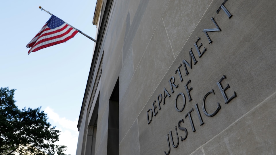 Shows the entrance to the headquarters of the US Department of Justice, which is written 